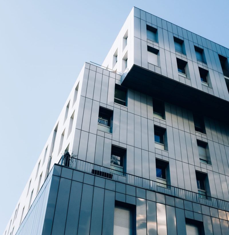 Low angle view of a modern skyscraper with glass windows set against a clear blue sky.